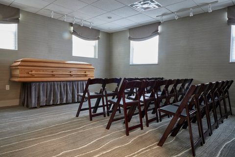Wood casket on draped stand with wooden folding chairs arranged for service at Sagel Bloomfield Danzansky Goldberg Funeral Care
